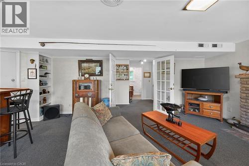 Carpeted living area featuring a built-in bar with barstools, recessed shelving, and a brick fireplace - 2 Summit Circle, Simcoe, ON - Indoor Photo Showing Living Room