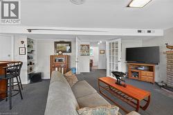 Carpeted living area featuring a built-in bar with barstools, recessed shelving, and a brick fireplace - 