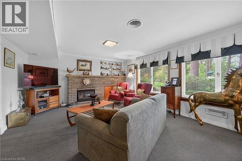 Living area featuring a brick-faced fireplace with a hearth, wall-to-wall carpeting, and multiple windows - 2 Summit Circle, Simcoe, ON - Indoor Photo Showing Living Room With Fireplace