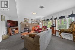 Living area featuring a brick-faced fireplace with a hearth, wall-to-wall carpeting, and multiple windows - 