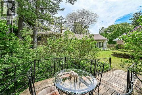 Wood-finish deck with decorative metal railings offering an elevated perspective of the expansive backyard - 2 Summit Circle, Simcoe, ON - Outdoor