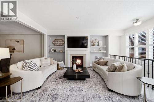 Living area featuring a fireplace with a white mantel, built-in shelving, white plantation shutters, and an open railing - 2466 Village Common, Oakville, ON - Indoor Photo Showing Living Room With Fireplace
