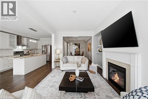 Open-concept living area featuring rich wood-finish flooring, a white mantel fireplace, and recessed lighting - 2466 Village Common, Oakville, ON - Indoor Photo Showing Living Room With Fireplace