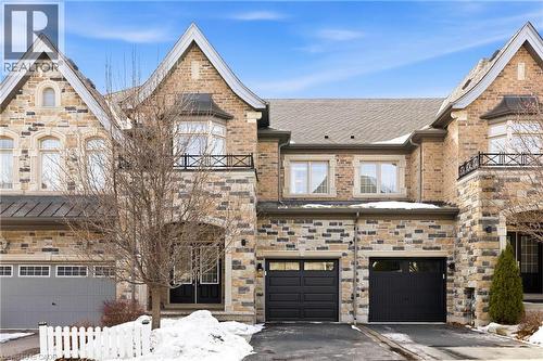 Stone and brick facade featuring multiple gables and a bay window with a wrought iron balcony - 2466 Village Common, Oakville, ON - Outdoor With Facade