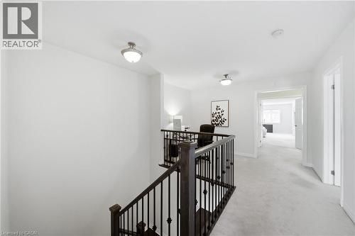 Upper-level landing featuring a wood staircase with wrought iron balusters, light gray carpet flooring, and recessed lighting - 2466 Village Common, Oakville, ON - Indoor Photo Showing Other Room