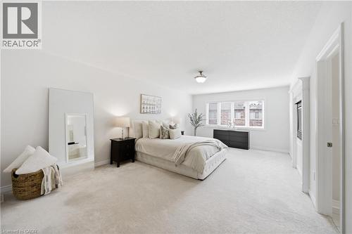 Spacious room featuring light-toned carpeting, a window providing natural light, a built-in media cabinet, and a flush-mount ceiling light fixture - 2466 Village Common, Oakville, ON - Indoor Photo Showing Bedroom