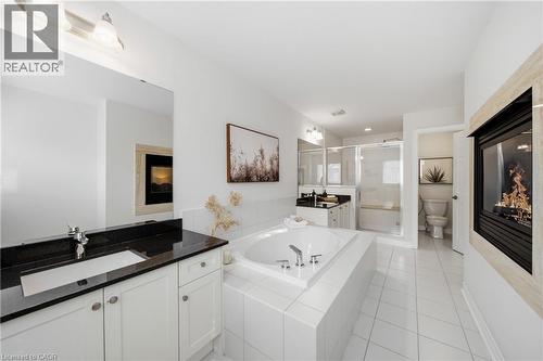 Bathroom featuring an integrated gas fireplace, a built-in soaking tub, dual vanity with dark countertops, and a glass-enclosed shower with a built-in bench - 2466 Village Common, Oakville, ON - Indoor Photo Showing Bathroom
