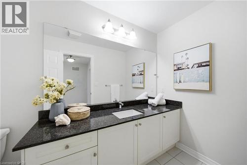 Vanity featuring a dark speckled countertop, integrated sink, and white cabinetry - 2466 Village Common, Oakville, ON - Indoor Photo Showing Bathroom
