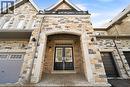 Stone and brick facade featuring a covered entry, black double doors with transom windows, and exterior wall sconces - 2466 Village Common, Oakville, ON  - Outdoor 