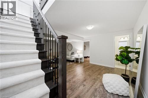 Entry foyer with wood-finish flooring, a carpeted staircase featuring wrought iron balusters, and a recessed ceiling light - 2466 Village Common, Oakville, ON - Indoor Photo Showing Other Room