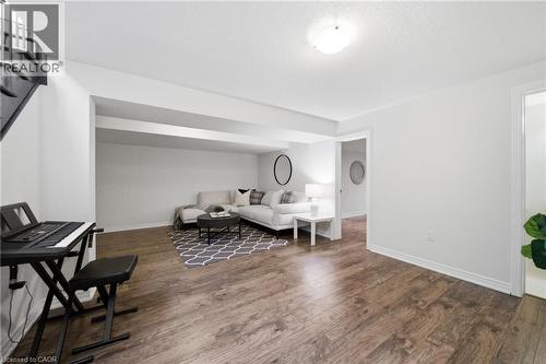 Spacious living area featuring wood-finish flooring, recessed ceiling beams, and a modern ceiling light fixture - 2466 Village Common, Oakville, ON - Indoor Photo Showing Other Room