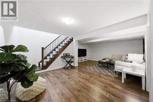 Spacious lower level featuring wood-finish flooring, a dark wood staircase with black iron spindles, white walls, and recessed ceiling lighting - 2466 Village Common, Oakville, ON - Indoor Photo Showing Other Room