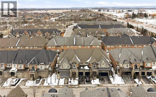 Residential street with a collection of properties featuring brick and stone facades, attached garages, and dormer windows - 2466 Village Common, Oakville, ON - Outdoor