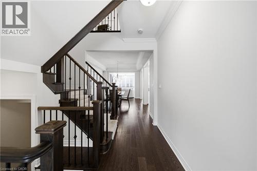 Multi-level staircase featuring dark wood newel posts and railings with decorative wrought iron balusters - 2466 Village Common, Oakville, ON - Indoor Photo Showing Other Room