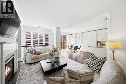 Bright living area featuring wood-finish flooring and a white fireplace with a mantel - 2466 Village Common, Oakville, ON - Indoor Photo Showing Living Room