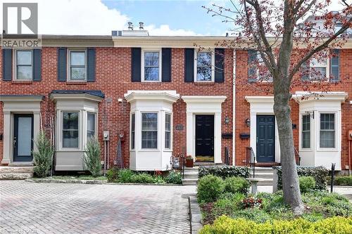 Brick facade townhome featuring bay windows, black shutters, and white trim accents - 463 Blathwayte Lane, Burlington, ON - Outdoor With Facade