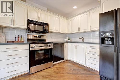 Kitchen featuring cream-colored cabinetry with decorative molding, a subway tile backsplash, and dark countertops - 463 Blathwayte Lane, Burlington, ON - Indoor Photo Showing Kitchen