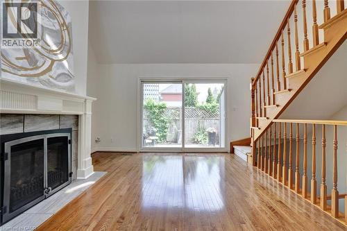 Living area featuring wood-finish flooring, a fireplace with a mantel and tile surround, and a natural wood staircase - 463 Blathwayte Lane, Burlington, ON - Indoor With Fireplace
