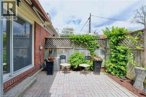 Expansive brick paver patio featuring a red brick exterior, large sliding glass door, wooden privacy fencing with lattice accents, and established perimeter plantings - 463 Blathwayte Lane, Burlington, ON - Outdoor With Deck Patio Veranda With Exterior