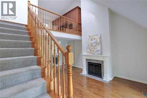 Hardwood flooring complemented by a carpeted staircase with wood banister - 463 Blathwayte Lane, Burlington, ON - Indoor Photo Showing Other Room With Fireplace