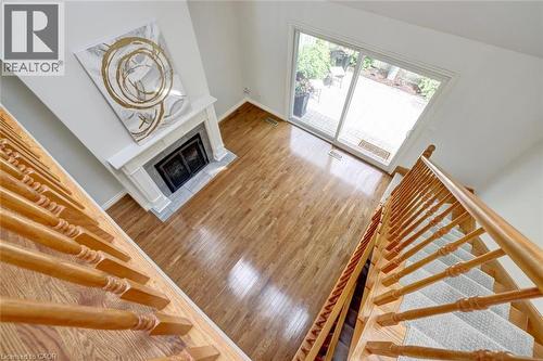 Living area featuring wood-finish flooring, a white mantel fireplace, and a sliding glass door to an outdoor patio - 463 Blathwayte Lane, Burlington, ON - Indoor Photo Showing Other Room With Fireplace