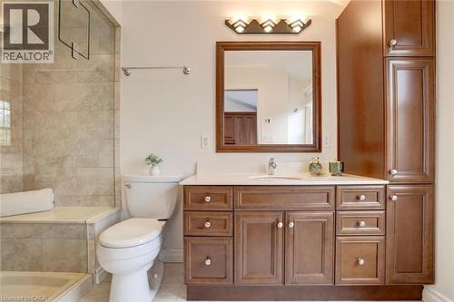 Bathroom featuring a wood-finish vanity with a light-colored countertop, integrated sink, and wall-mounted mirror - 463 Blathwayte Lane, Burlington, ON - Indoor Photo Showing Bathroom
