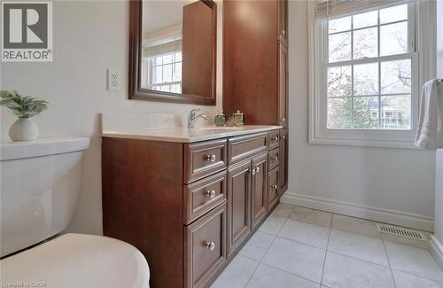 Bathroom featuring a single-sink vanity with wood cabinetry, light-toned countertop, framed mirror, and a window with natural light - 463 Blathwayte Lane, Burlington, ON - Indoor Photo Showing Bathroom