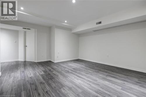 Spacious room featuring wood-finish flooring, recessed lighting, white walls, and white baseboards - 463 Blathwayte Lane, Burlington, ON - Indoor