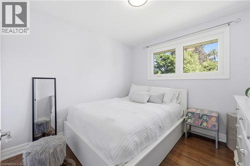 Light-filled room featuring wood-finish flooring, white trim, and a window with a treed outlook - 168 Nugent Drive, Hamilton, ON - Indoor Photo Showing Bedroom