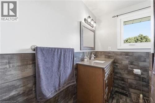 Bathroom featuring wood-finish wall paneling, a single vanity with a light-toned countertop, and a window with exterior tree scenery - 168 Nugent Drive, Hamilton, ON - Indoor Photo Showing Bathroom