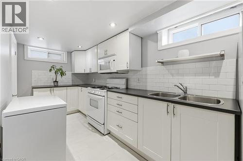 Contemporary kitchen featuring white cabinetry with brushed nickel hardware, dark countertops, white subway tile backsplash, and a double basin stainless steel sink - 168 Nugent Drive, Hamilton, ON - Indoor Photo Showing Kitchen With Double Sink