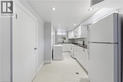 Full kitchen featuring white cabinetry, dark countertops, white subway tile backsplash, and recessed lighting - 168 Nugent Drive, Hamilton, ON - Indoor Photo Showing Kitchen