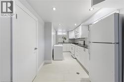 Full kitchen featuring white cabinetry, dark countertops, white subway tile backsplash, and recessed lighting - 