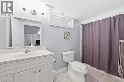 Bathroom featuring a white vanity with integrated sink, chrome faucet, wall-mounted mirror, and overhead vanity lighting - 168 Nugent Drive, Hamilton, ON - Indoor Photo Showing Bathroom