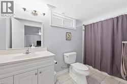 Bathroom featuring a white vanity with integrated sink, chrome faucet, wall-mounted mirror, and overhead vanity lighting - 