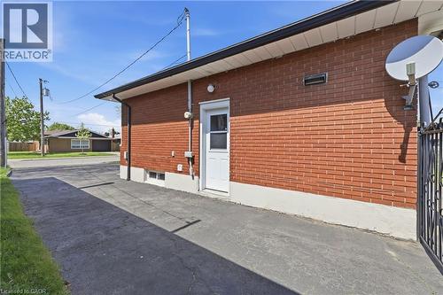Red brick exterior with white trim, featuring a white entry door with a privacy screen - 168 Nugent Drive, Hamilton, ON - Outdoor With Exterior
