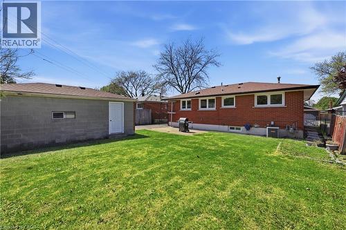 Expansive green lawn with a detached block garage featuring a side entry door and a single window - 168 Nugent Drive, Hamilton, ON - Outdoor With Exterior