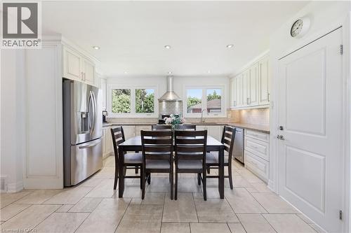 Bright kitchen featuring extensive white cabinetry, stainless steel appliances, recessed lighting, and large windows - 168 Nugent Drive, Hamilton, ON - Indoor