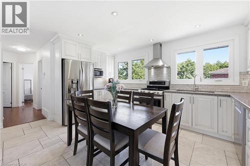 Bright kitchen featuring white cabinetry, stainless steel appliances, light-toned tile flooring, and multiple windows - 168 Nugent Drive, Hamilton, ON - Indoor