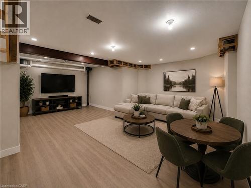 Open-concept living space featuring wood-finish flooring, recessed lighting, exposed ceiling beams, and a built-in media console - 16 Glennie Court, Cambridge, ON - Indoor