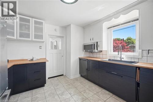 Kitchen featuring dark base cabinetry, wood-finish countertops, and a stainless steel over-the-range microwave - 94 Clarendon Avenue, Hamilton, ON - Indoor Photo Showing Kitchen