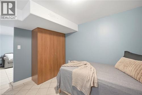 Room featuring light blue walls, ceramic tile flooring, and a built-in wood-finish wardrobe - 94 Clarendon Avenue, Hamilton, ON - Indoor Photo Showing Bedroom