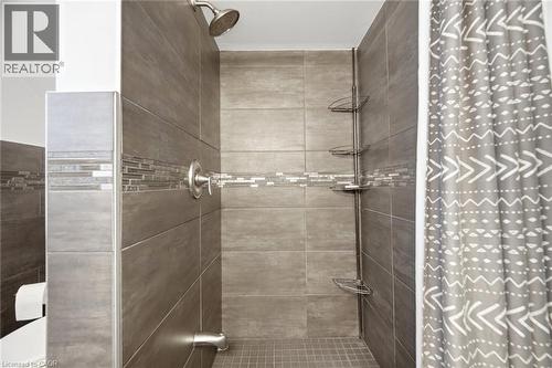 Tiled shower enclosure featuring a mosaic accent band and a rain showerhead - 94 Clarendon Avenue, Hamilton, ON - Indoor Photo Showing Bathroom