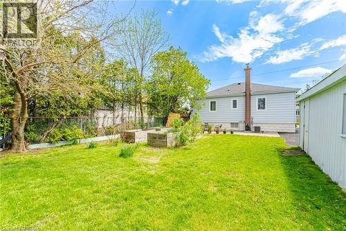 Expansive rear yard featuring a verdant lawn, mature trees, and raised garden beds - 94 Clarendon Avenue, Hamilton, ON - Outdoor