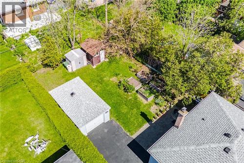 Expansive property featuring a detached garage with asphalt driveway, two distinct outbuildings, and multiple raised garden beds - 94 Clarendon Avenue, Hamilton, ON - Outdoor