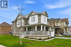 Brick and stone facade residence featuring a covered front porch with white railings and columns - 