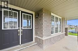 Welcoming double entry doors with transom windows, a concrete porch, exterior brick siding, and an overhead porch light - 