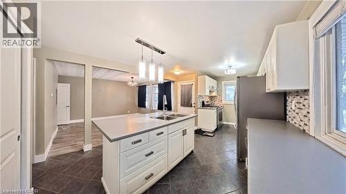 Kitchen featuring a central island with dual sinks, white shaker-style cabinetry, dark tile flooring, and a mosaic tile backsplash - 61 Bosworth Crescent Unit# Upper, Kitchener, ON - Indoor Photo Showing Kitchen With Double Sink