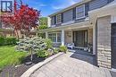 Gray siding exterior with stone accents, a covered front porch, a dark paneled entry door, and a paver walkway - 3500 Regal Road, Burlington, ON  - Outdoor With Deck Patio Veranda 