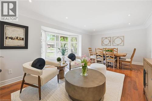 Hardwood flooring throughout a bright living and dining area featuring a bay window with plantation shutters, recessed lighting, and crown molding - 3500 Regal Road, Burlington, ON - Indoor